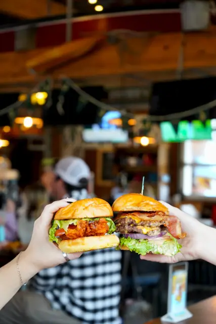 A crispy chicken sandwich and a bacon cheeseburger held up together
