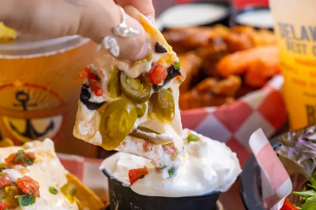 A loaded nacho chip with jalapeños and queso
